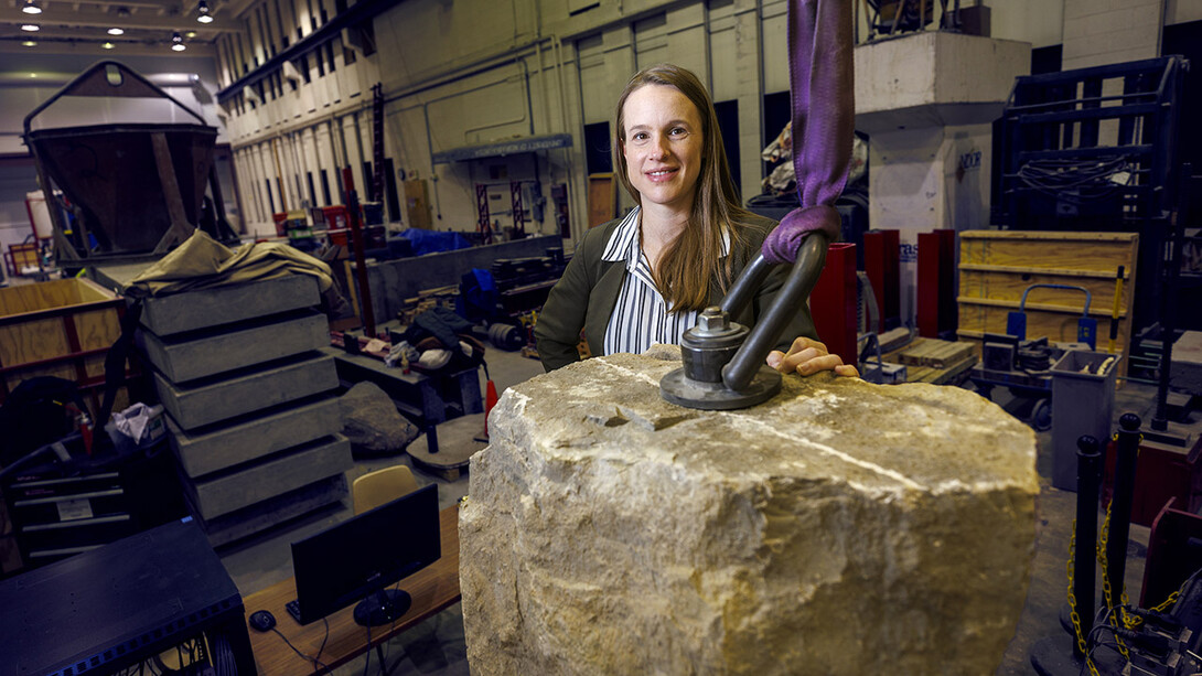 Christine Wittich standing behind giant rock in cluttered workshop