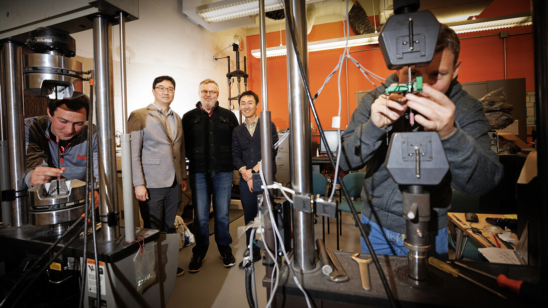Husker engineers Jongwan Eun (center left), Yuris Dzenis (center) and Seunghee Kim (center right) pose in Dzenis’ lab as Benjamin Bashtovoi (left), a junior mechanical engineering major, and Mikhail Kartashov (right), an engineering graduate student, test carbon-fiber samples. Eun, Dzenis and Kim have received $675,000 from the Department of Energy’s Established Program to Stimulate Competitive Research to investigate how inorganic microfibers can make a more resilient barrier material to im