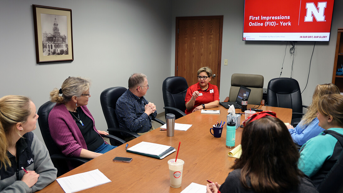 Seven people gather around a conference table.