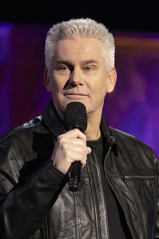 Brian Regan appears onstage, holding a microphone.