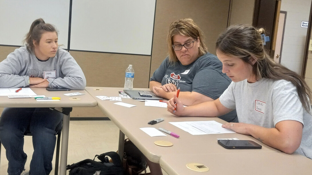 Three female teachers sit at tables.