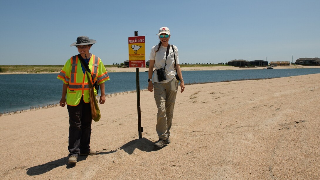 Caitlin Copenhaver (left) and Elsa Forsberg with the Tern and Plover Conservation Partnership stand next to a sign that closes a beach area to protect the nesting least terns and piping plovers.