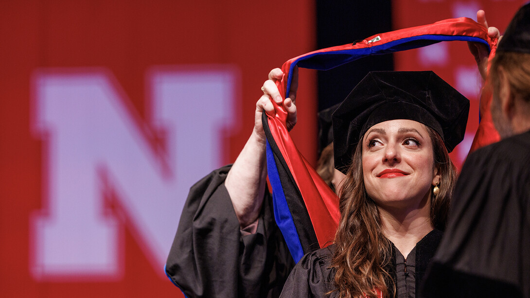 Sonia Lindner watches as her doctoral hood is placed over her head.