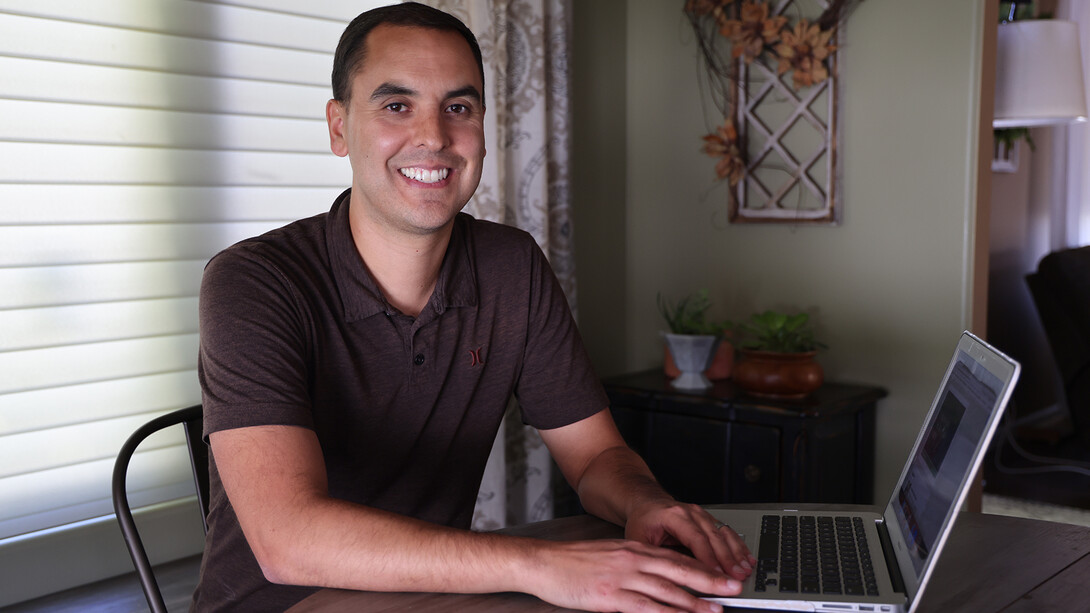 Jon Alvarado sits at a table with his laptop.