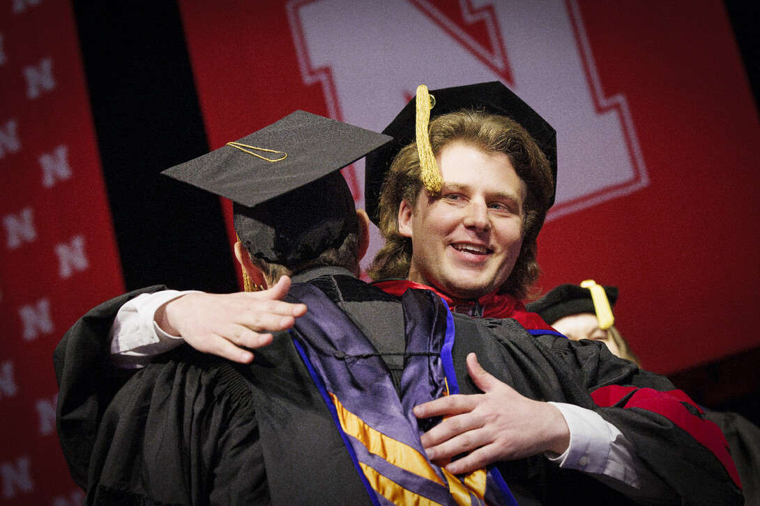 Andrew Loken of Hickman hugs Joshua Steelman, associate professor of environmental and civil engineering, on stage at commencement.