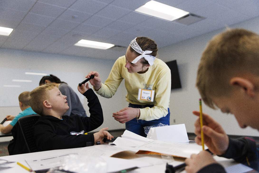 A young woman helps a boy with his Galaxy Quest activity.