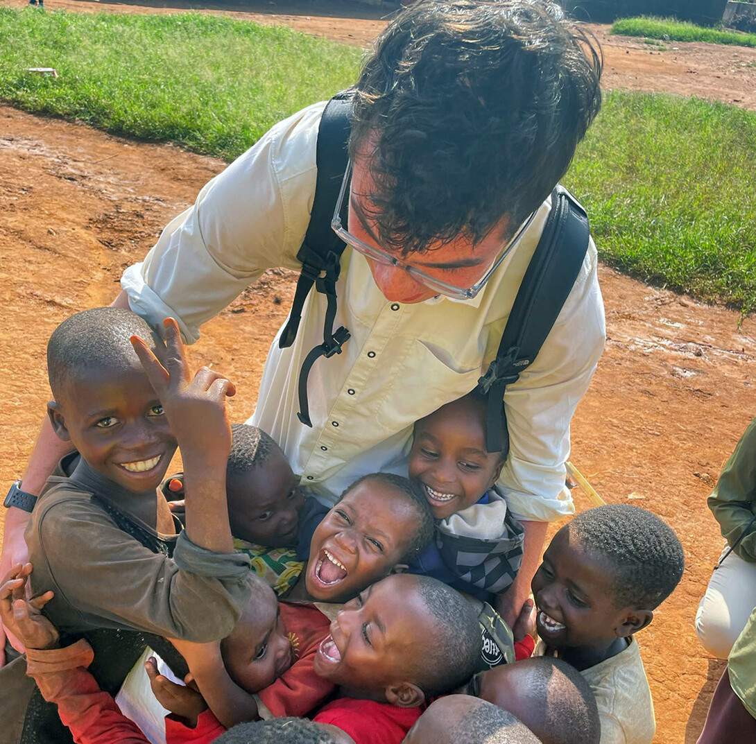 A student is surrounded by Rwandan youth during the study abroad trip.