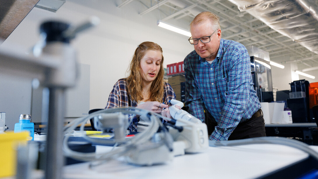 Rachael Wagner and Shane Farritor look over a robotic surgery device in the Virtual Incision facility.