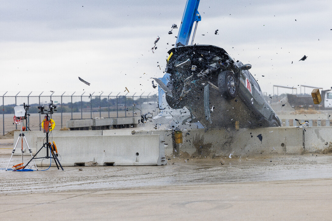 The front end of a pickup is raised in the air as it hits a concrete barrier.