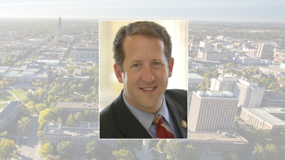 Color photo of Adrian Smith on color campus background