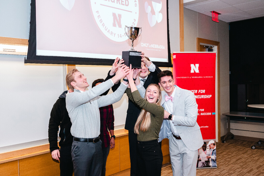 Five young men and a young woman hold up a trophy.