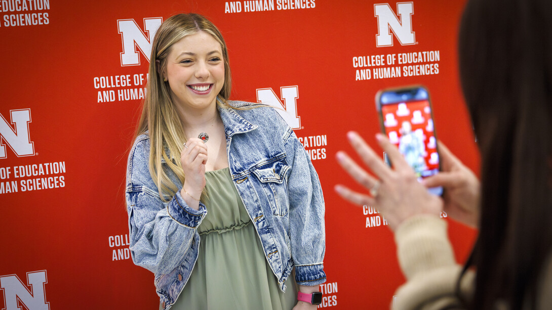 Second-year student Taylor Kirlin holds up a commemorative pin as she poses for a smartphone photograph.