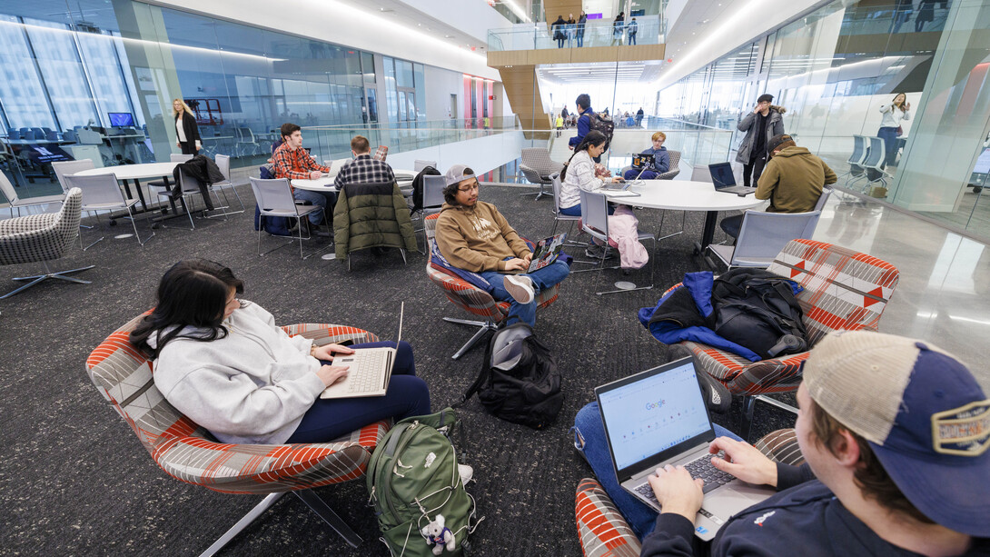 Eight students sit in a study area in Kiewit Hall.