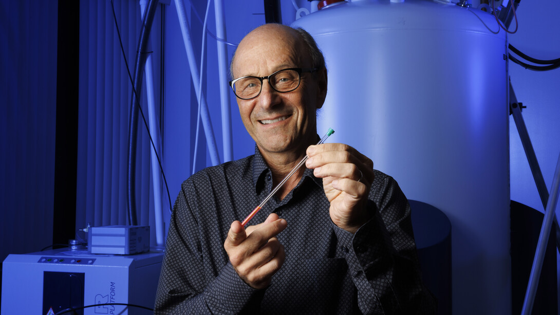 David Berkowitz holds a nuclear magnetic resonance tube in a lab.