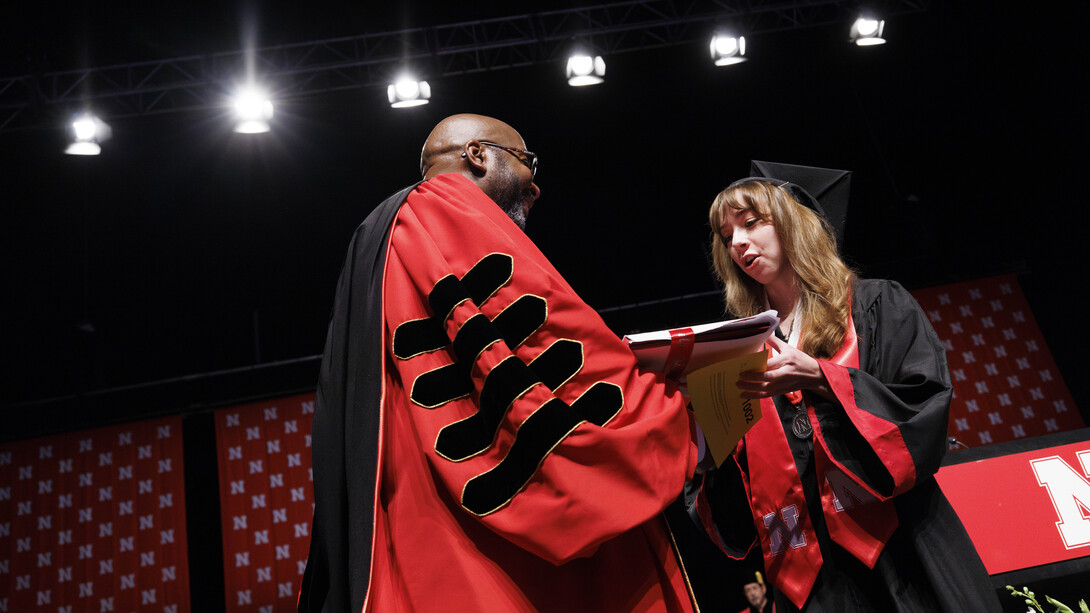 Kylee Preuss of Omaha (right) receives her diploma from Chancellor Rodney D. Bennett during the combined graduate and undergraduate commencement ceremony Aug. 17 at Pinnacle Bank Arena.