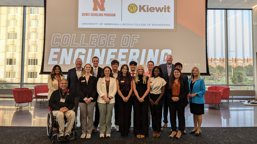 Ten Kiewit Scholars, College of Engineering Dean Lance C. Pérez and six Kiewit representatives pose for a photo in front of a screen that reads "College of Engineering."