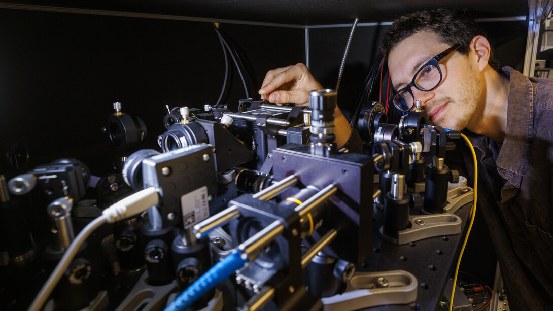 Adam Erickson adjusts a large, complex microscope.