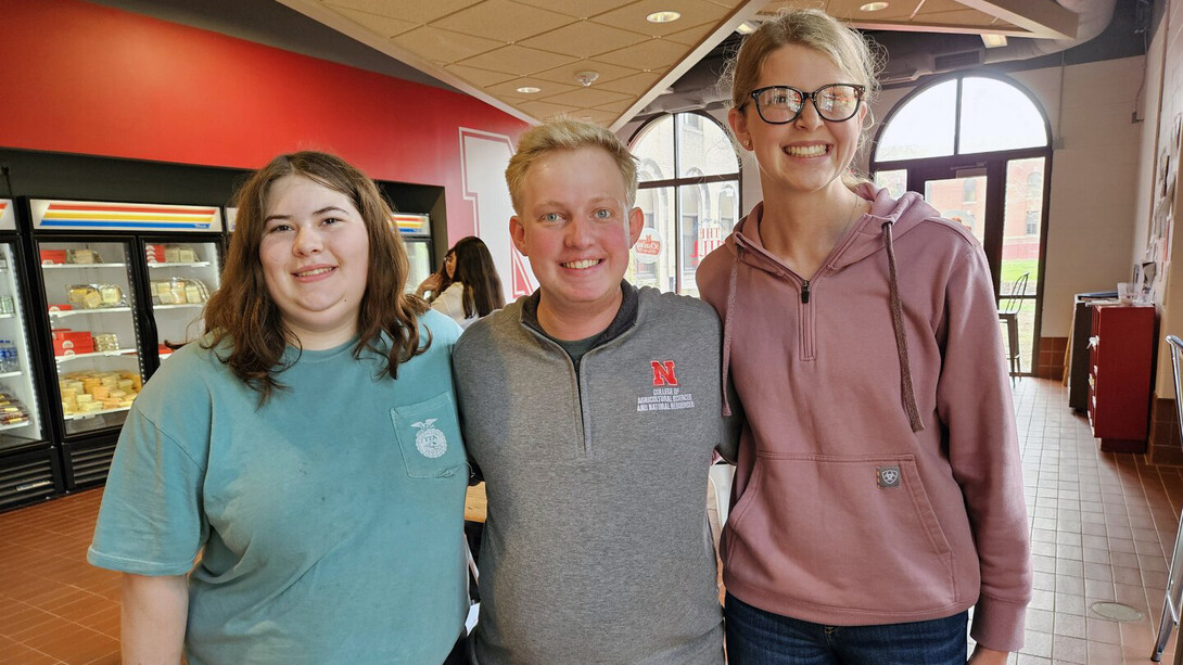 Carie Goodwater (left) and Melany Preister (right), students at Boone Central High School, pose with Brian Mock (center), a Husker student mentor who graduated in May, at the UNL Dairy Store.