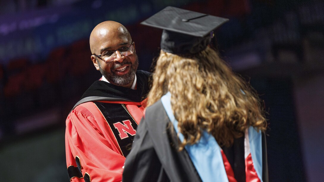 Chancellor Rodney D. Bennett congratulates a graduate on stage at Pinnacle Bank Arena.