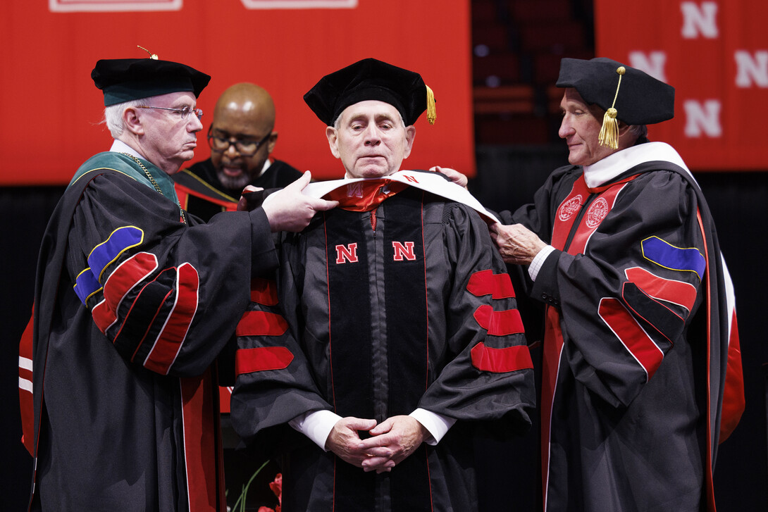 Ken M. Bird receives his honorary Doctor of Education hood from Dr. Jeffrey P. Gold (left), president of the University of Nebraska system, and Regent Jack Stark (right) during the graduate and professional degree ceremony.