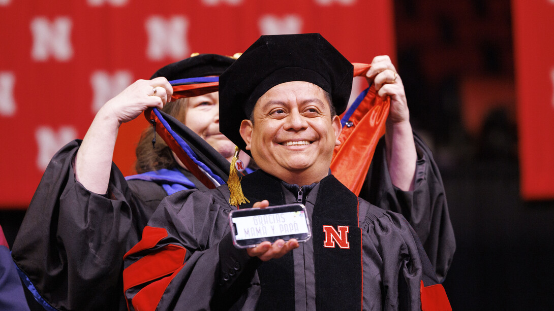 Héctor de Jesús Palala Martínez of Guatemala smiles as he displays the phrase “Gracias Mama y Papa” before receiving his doctoral hood.