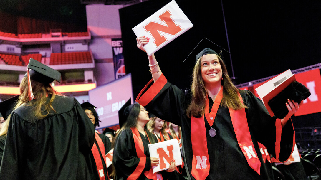 Alexis Marie Gray of Omaha raises her diploma to her family in the crowd during the undergraduate commencement ceremony Dec. 21 at Pinnacle Bank Arena.