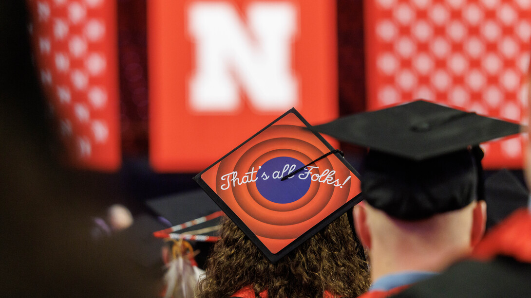 A graduate wears a mortar board decorated with the phrase "That's all, folks" during the undergraduate commencement ceremony Dec. 21 at Pinnacle Bank Arena.