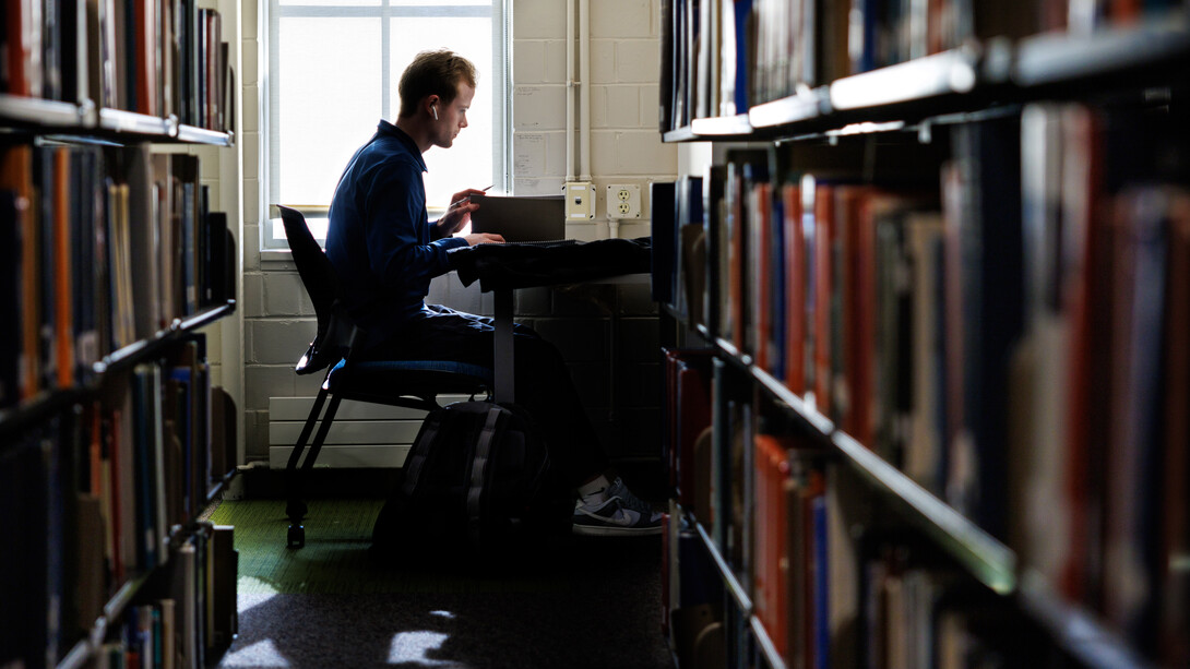 Camden Hjermstad, a freshman mechanical engineering major, studies at a desk in Love Library South on Dec. 2. The desk is at the end of a row of bookcases.