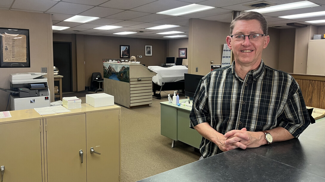 Kurt Johnson, publisher of the Aurora News-Register, leans against a counter in his newsroom.