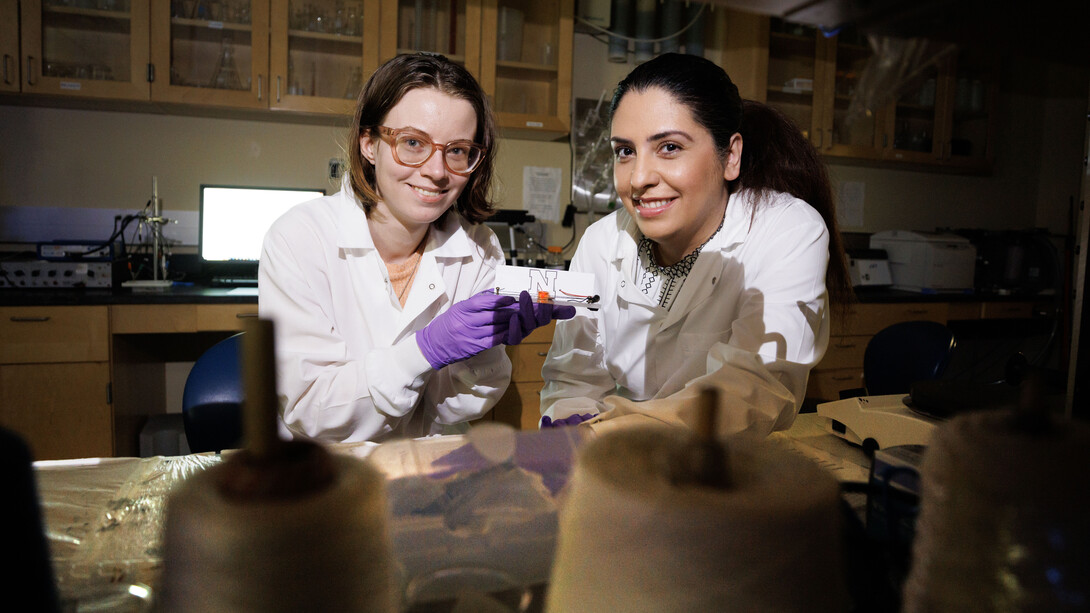 Alyssa Grube (left), a graduate student in chemical and biomolecular engineering, and Mona Bavarian, assistant professor of chemical and biomolecular engineering, hold a textile-based supercapacitor.