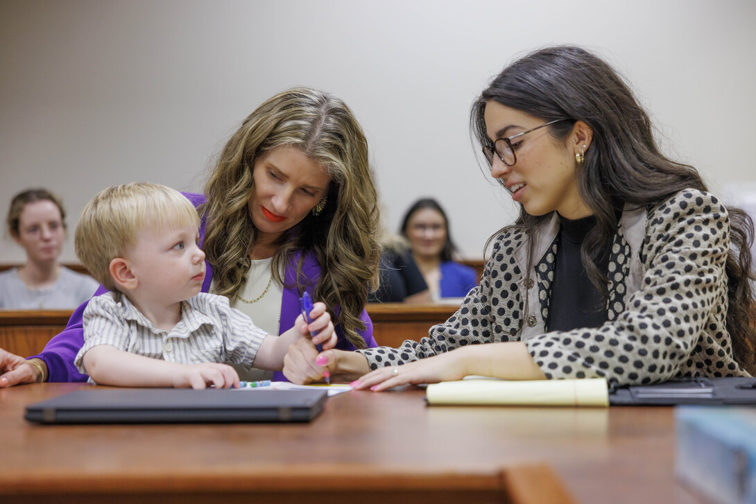Michelle Paxton (left), director of the Nebraska Children's Justice and Legal Advocacy Center and assistant professor of law, and Carmella Perkins, then a third-year law student, interact with a young boy during a courtroom simulation in August 2024.