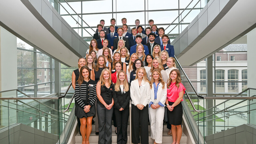 About 40 students in formal attire — all pursuing their undergraduate certificate in sales excellence from the University of Nebraska–Lincoln — stand on a staircase in Howard L. Hawks Hall.