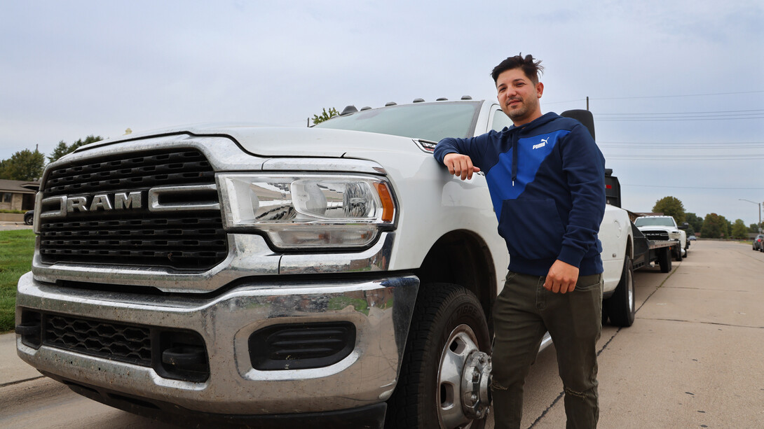 Joel Yera, owner of Yera Transportation, stands next to a white Ram truck on the side of a street.
