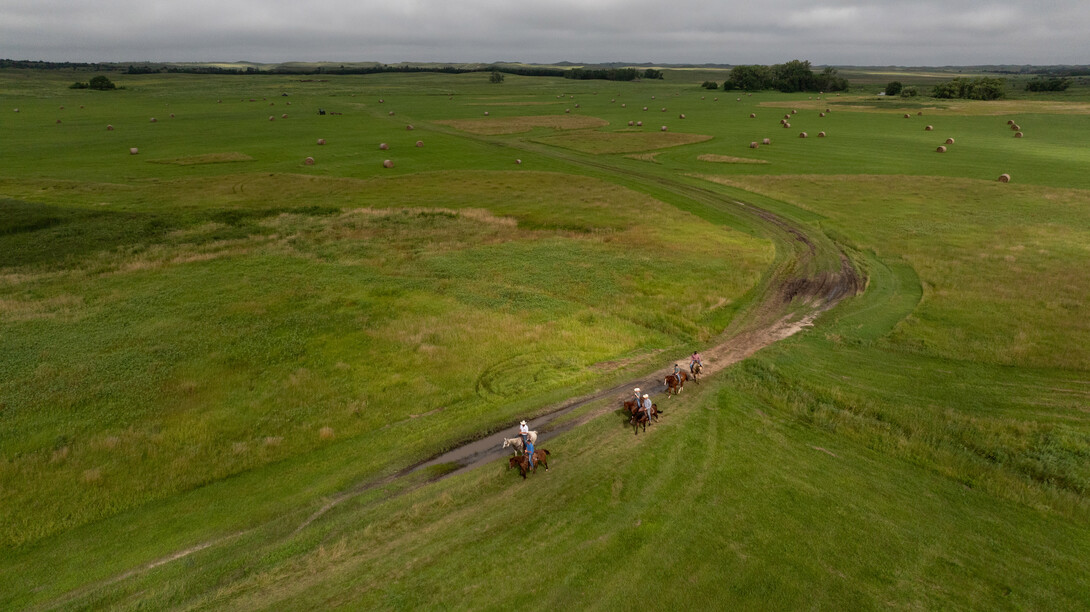 An aerial photo of six ranchers riding horses in the Nebraska Sandhills.