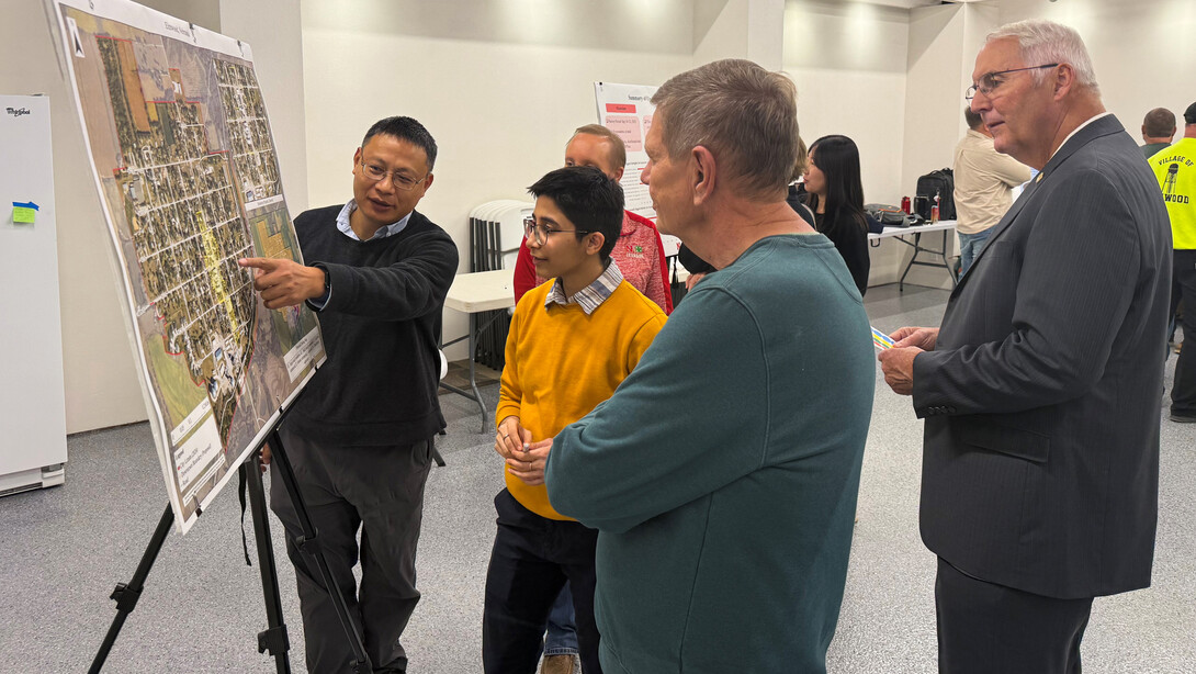 Zhenghong Tang, professor of community and regional planning, highlights the proposed downtown boundary for the village of Elmwood to community members at an open house. 
