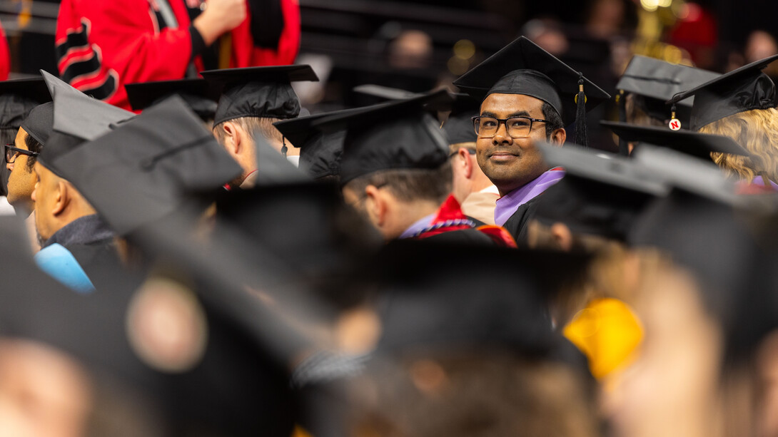Md Asaduzzaman Noor, seated among fellow graduates, looks for family and friends in the audience during the graduate and professional degree ceremony Dec. 19 at Pinnacle Bank Arena.