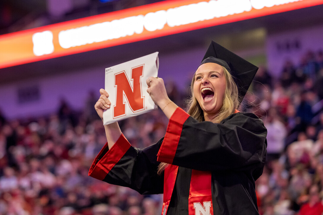 Emily Nordby, dressed in graduation regalia, shows off her newly earned Bachelor of Science in Education and Human Sciences during the undergraduate commencement ceremony Dec. 20 at Pinnacle Bank Arena.