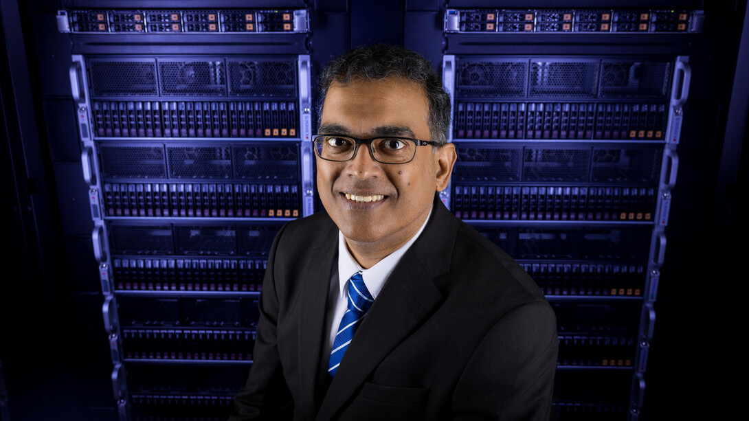 Byrav Ramamurthy, professor of computing at the University of Nebraska–Lincoln, stands in front of server racks in a blue-lit room.