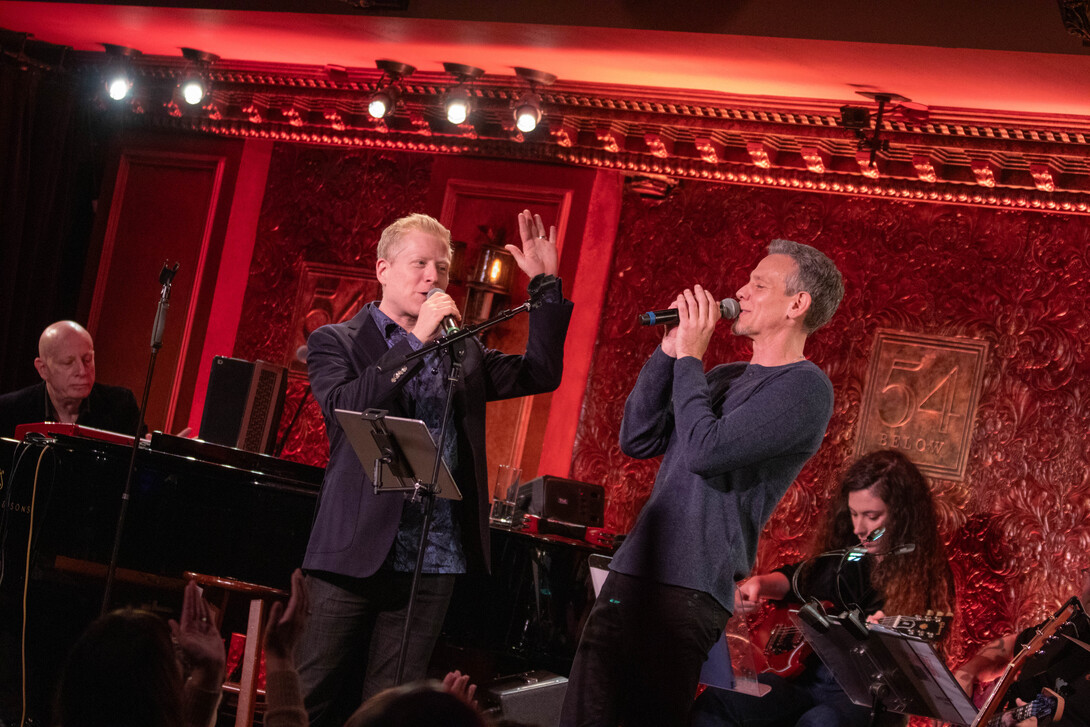 Broadway stars Anthony Rapp (left) and Adam Pascal perform with a small ensemble in an elegant room.