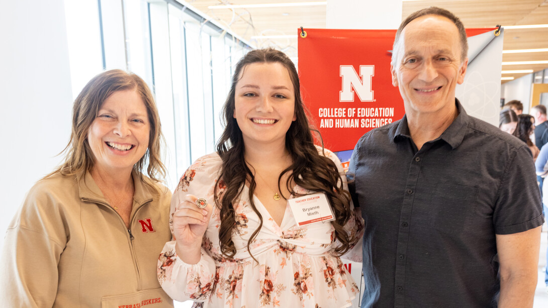 Bryanne Mieth (center), an elementary education major from Lincoln, holds her pin while posing for a photo with her parents, Carla (left) and Bruce (right), after the Teacher Education Convocation on April 17.