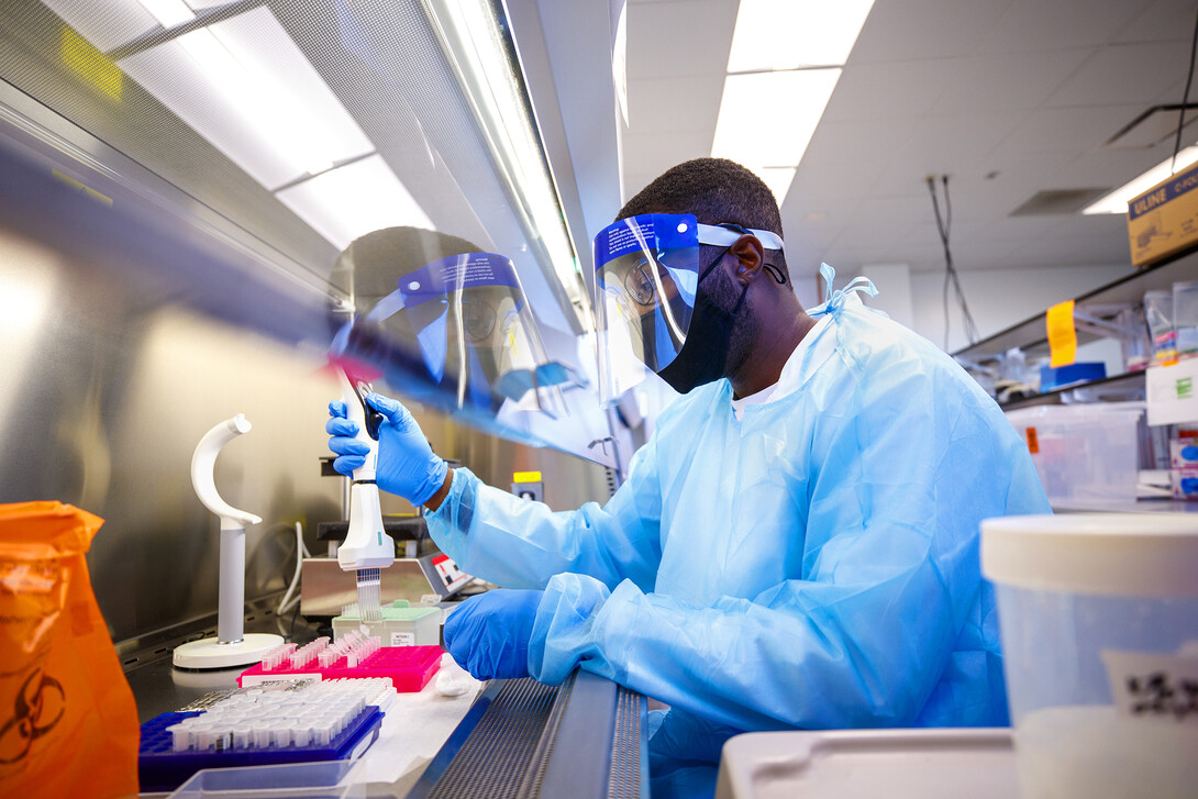 Edwin Owusu transfers saliva samples to other tubes where the saliva will be treated which kills any virus and the sample can be safely handled and tested for COVID-19. Saliva-based diagnostic testing program is managed by the university through lab space in the Veterinary Diagnostic Center.