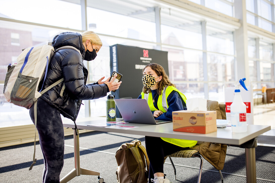 Katie Lockyear, a wellness attendant (right), checks a status card as Huskers enter Hawks Hall at the start of the spring 2021 semester.