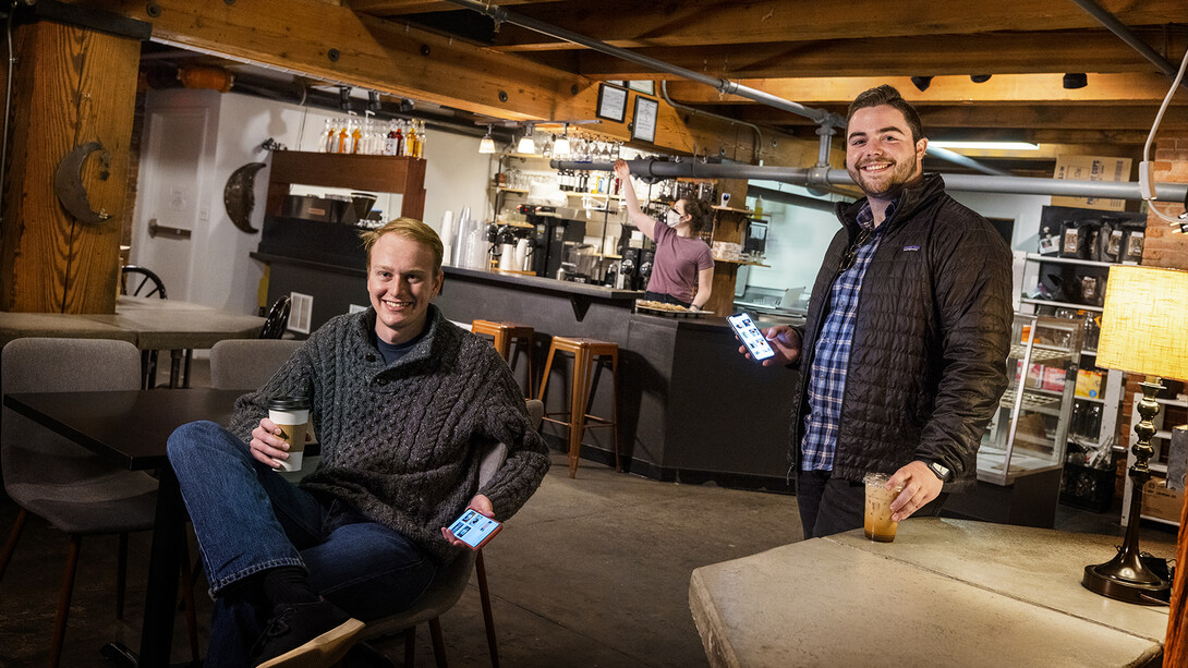 Jarod Aerts (left) and Luke Bogus, students in the Jeffrey S. Raikes School of Computer Science and Management, along with Jacob Peddicord (not pictured) are the creators of Brim, a mobile ordering app that is compatible with any business that uses the payment system Square. Aerts and Bogus are sitting in Crescent Moon Coffee, one of their clients, in the Haymarket.