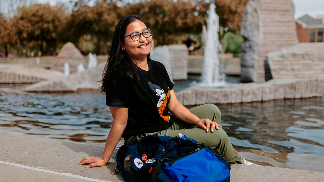 Sandhya Karki sitting next to Broyhill Fountain at the University of Nebraska–Lincoln.