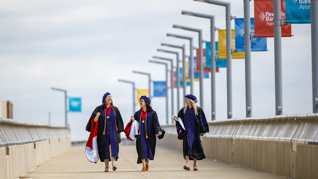 Nebraska Law graduates (from left) Claudia Brock, Sarah O’Neill and Rachel Lowe walk across the pedestrian bridge toward Pinnacle Bank Arena before commencement on May 7.