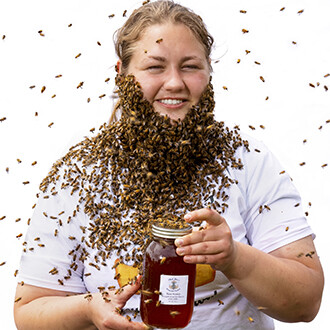 Photo of Shelby Kittle holding a jar of honey and wearing a beard made of bees.