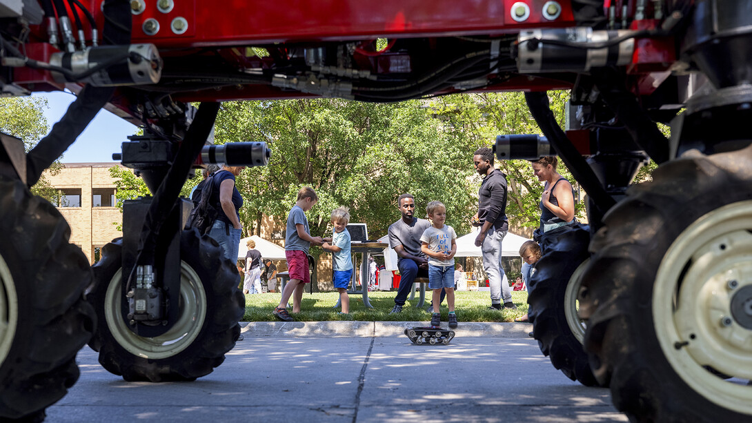 Youth play near a tractor as parents look on during East Campus Discovery Days on June 12. Craig Chandler | University Communication