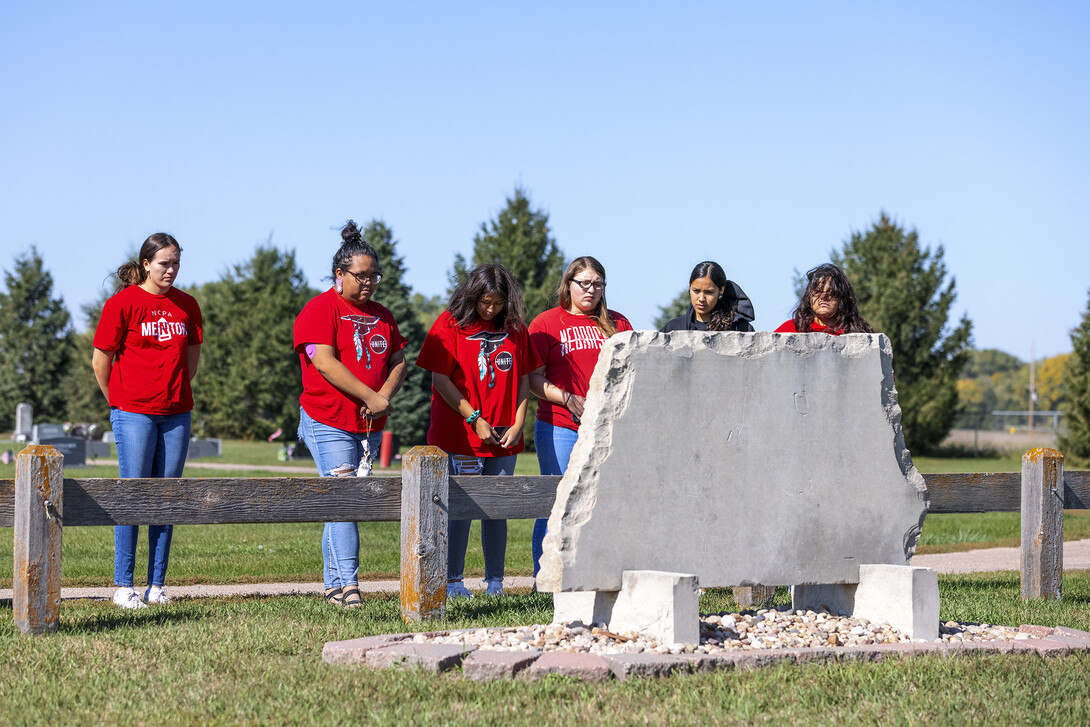 Students pause at a marker in the Genoa Cemetery marking Pawnee who were reburied during ceremonies in the 1990s.