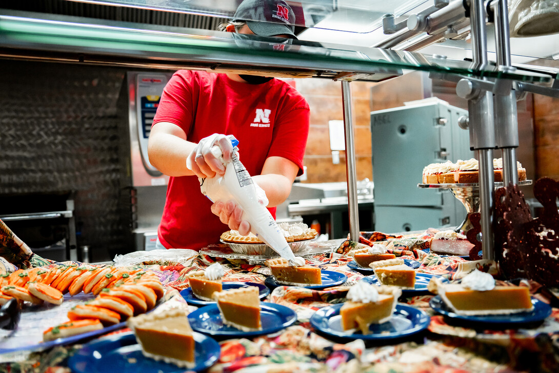 A Dining Services employee tops off the pumpkin pie with a dollop of whipped cream.