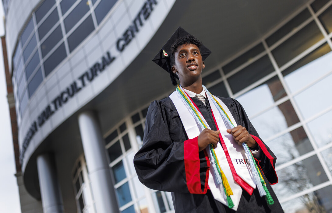 Khalid Yusuf, who served as a Diversity Ambassador, stands in his graduation regalia near the Gaughan Multicultural Center.